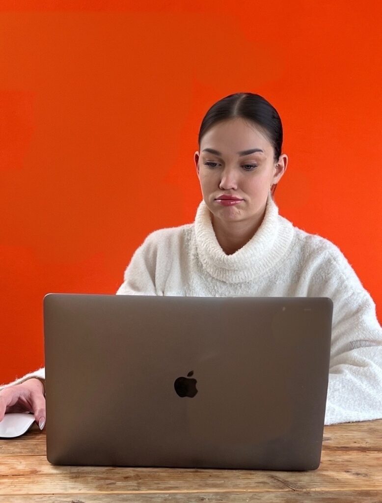 Wenn du mit einem konkreten Problem nicht weiter kommst, ist der Webdesign Workshop genau das richtige für dich. Auf dem Foto siehst du eine junge Frau, die mittlerweile frustriert vor ihrem Macbook sitzt.